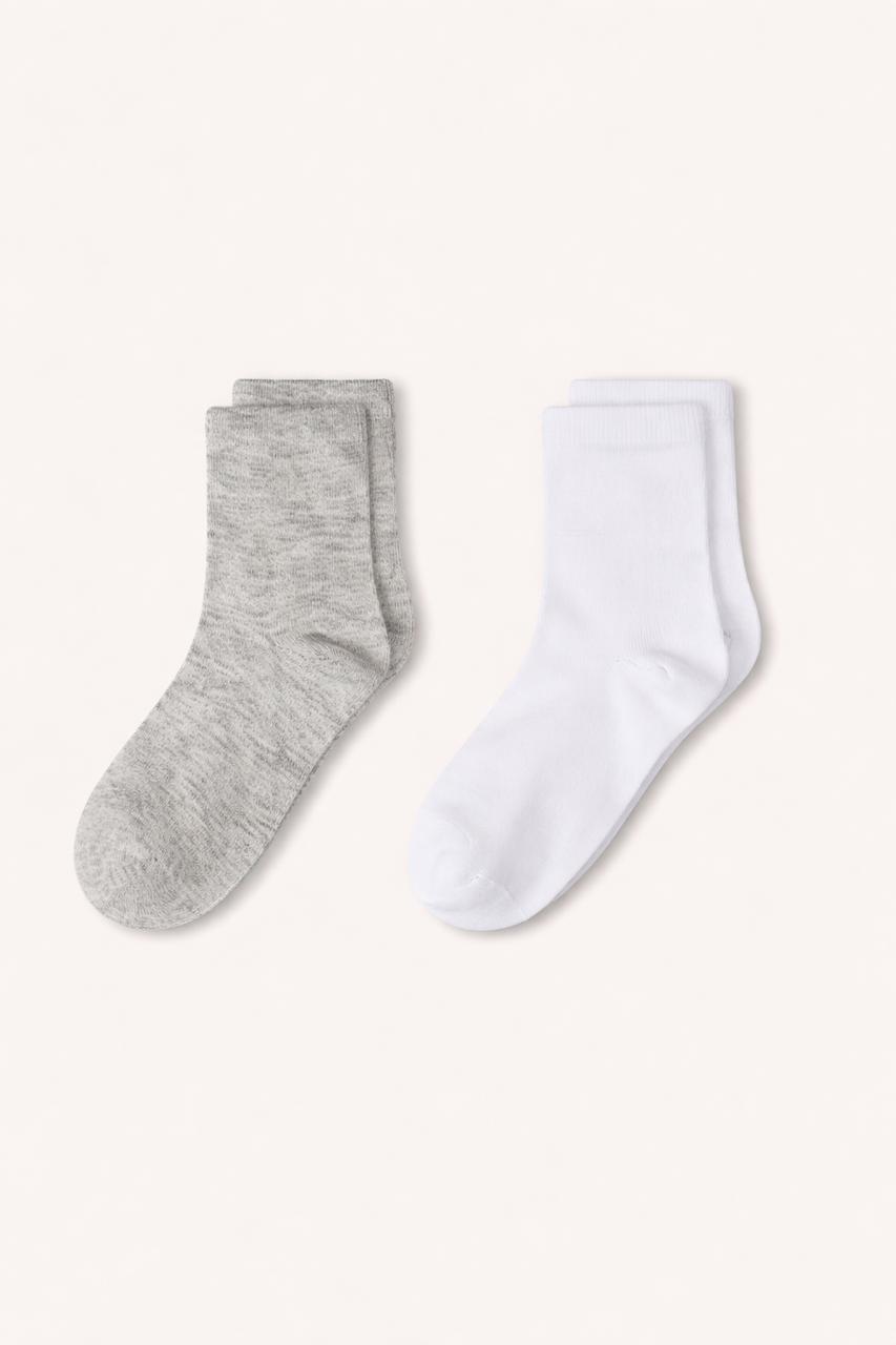 Two pairs of socks, one gray and one white, on a white background